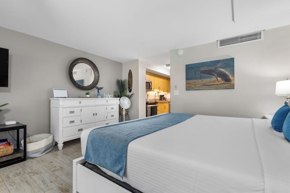 Your peaceful bedroom features a plush bed and connects to a well-equipped kitchenette, blending coastal charm with modern comfort for your relaxing getaway.