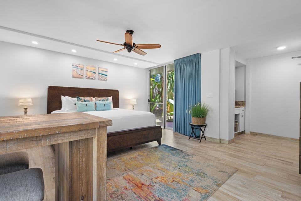 Unwind in your coastal-inspired bedroom, with a plush king bed, calming ocean hues, and breezy doors opening to tropical greenery just steps away.