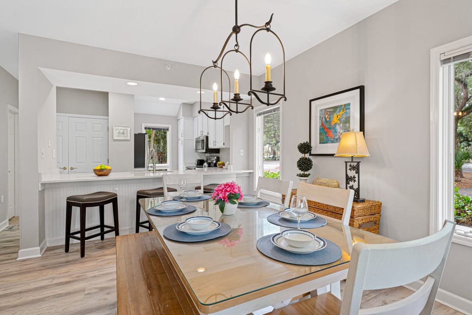The dining area flows seamlessly into the kitchen, featuring a glass-top table with bench seating and a breakfast bar for casual meals.