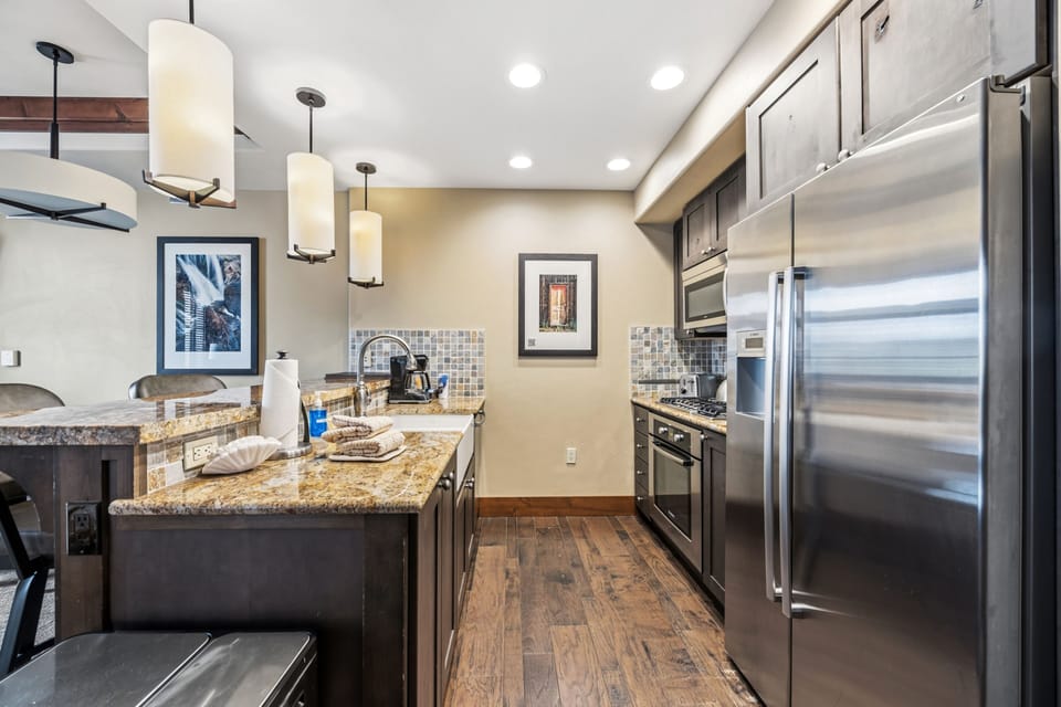 Kitchen galley with mosaic tile and full stainless appliance set.