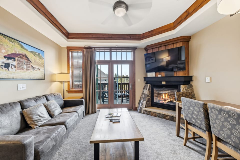 Living room with framed alpine art and gas hearth.