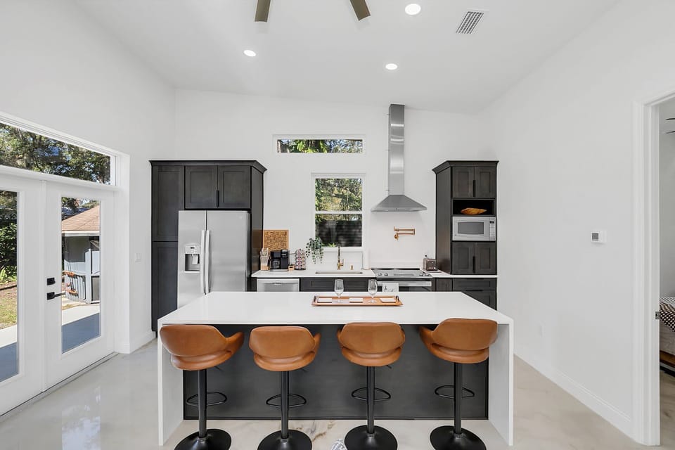 Modern kitchen with a large island and leather bar stools for casual dining.