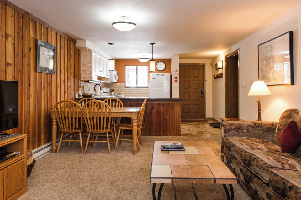 Your cozy mountain retreat features rustic wood paneling, a fully equipped kitchen, and comfortable seating where you can unwind after your adventures.