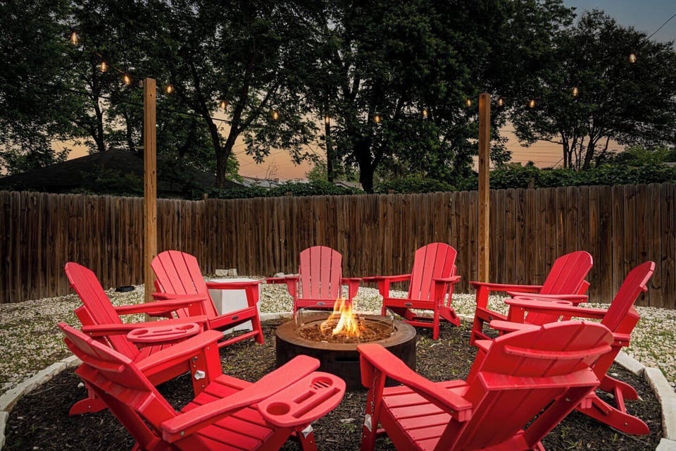 Backyard Paradise: Gather around the firepit in vibrant red chairs under twinkling lights!