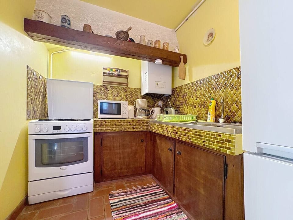 Cuisine provençale, avec gazinière, réfrigérateur, congélateur, micro-ondes et ustensiles.