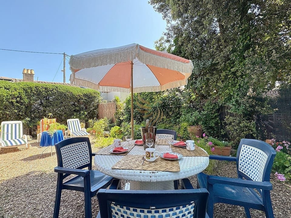 Un jardin privatif verdoyant et sans vis-à-vis avec coin repas, une grande table et ses quatre chaises.