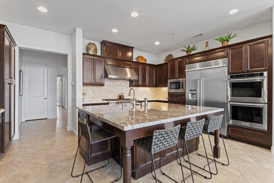 Spacious kitchen w/ granite island, bar stools & stainless appliances for easy meals