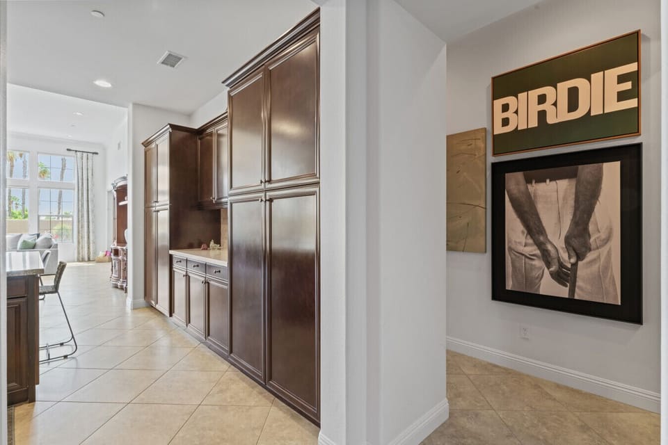 Hallway w/ built-in storage leading to bright spaces & golf-inspired wall art