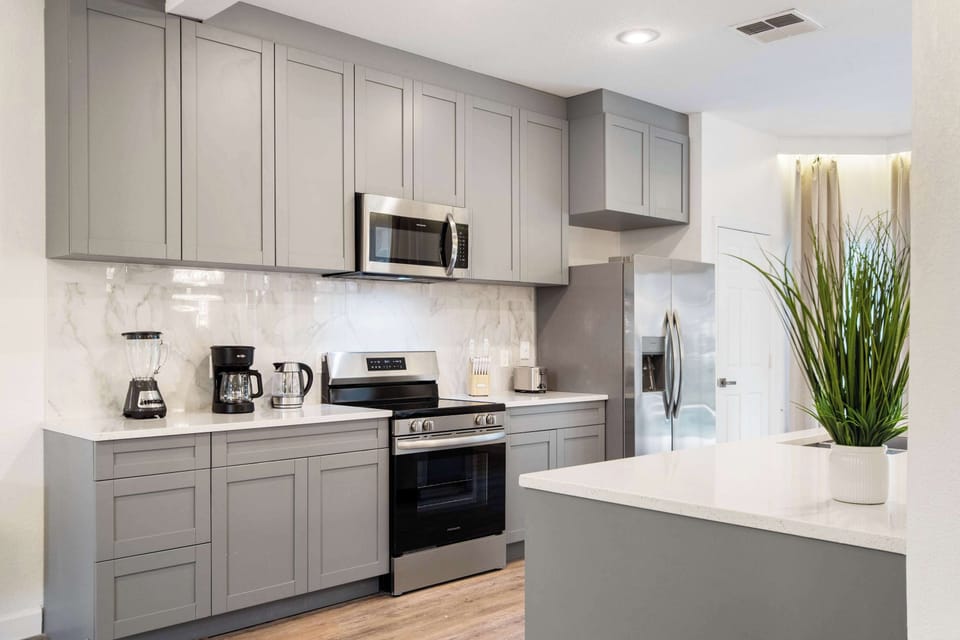 Sleek gray cabinetry, marble backsplash, and stainless steel appliances. 