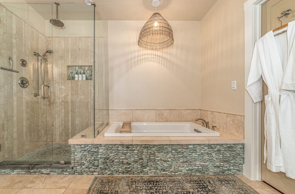 The primary en suite bathroom has a dual head rainfall shower, soaking tub and double vanity.