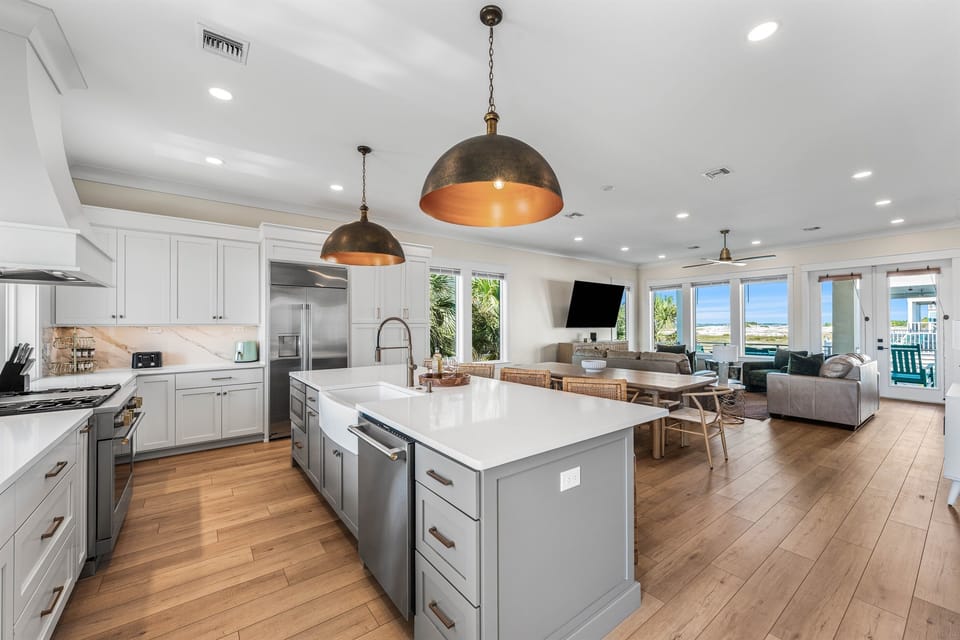 You'll love cooking in this spacious gourmet kitchen with sleek countertops, modern appliances, and warm pendant lighting overlooking your ocean-view living space.