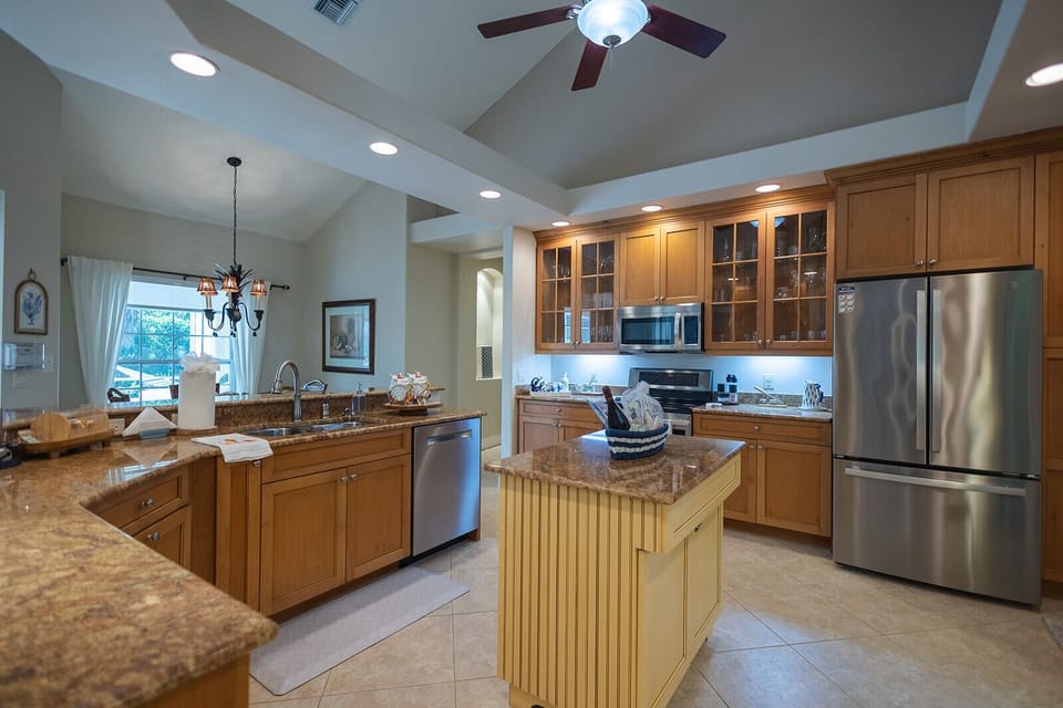 Bright open kitchen with granite counters, island, and stainless appliances.