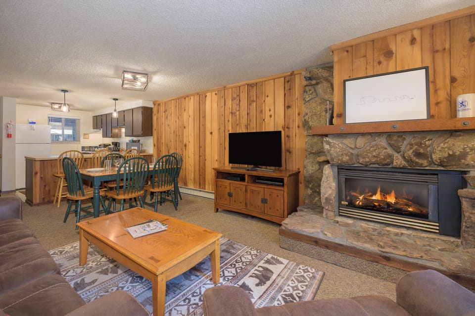 Cozy up in your mountain retreat with warm wood paneling, crackling fireplace, and open living space perfect for relaxing after adventure-filled days.