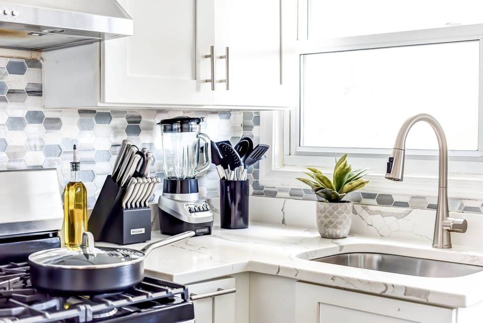 Cook up a storm in our stylish kitchen with quality cookware, a gas stove, and geometric backsplash, all set against window views.