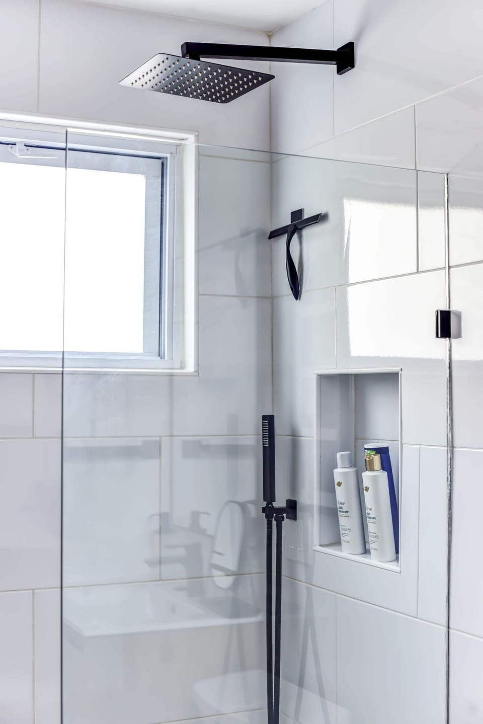 Refresh and rejuvenate in a luxurious bathroom with a rainfall shower, niche shelving, and abundant natural light.