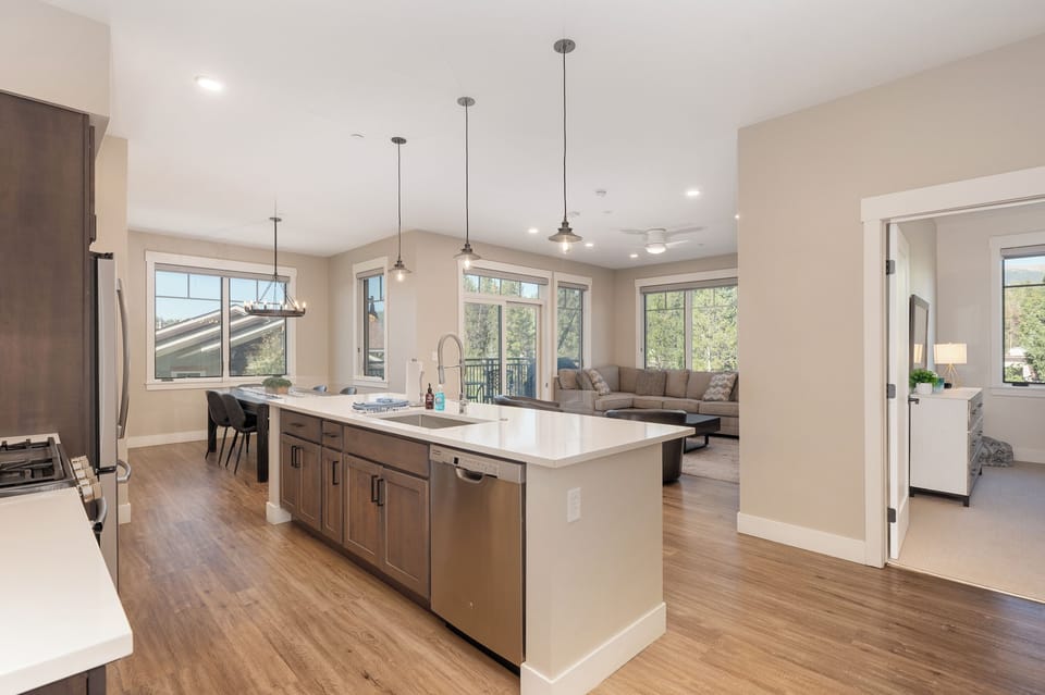 - Spacious open concept layout with a large center island and stylish pendant lighting - Fully equipped kitchen with stainless steel appliances and seating for casual meals - Flows seamlessly into a cozy living room with forest views