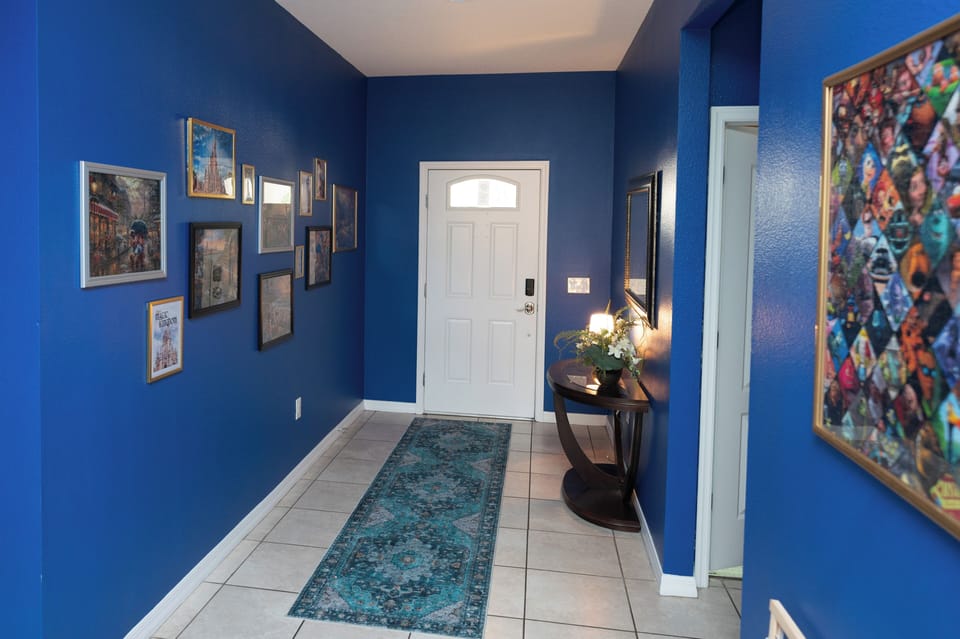 Vibrant, art-filled entry with smart lock, tile floors, and warm lighting.
