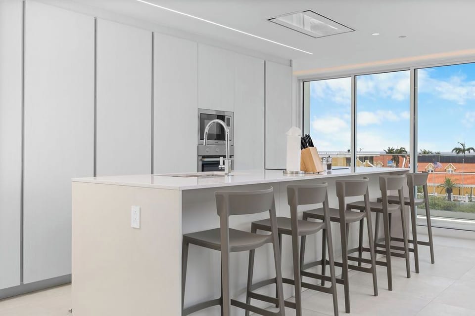 Your sleek kitchen awaits with a spacious island for morning coffee, stainless appliances ready for home-cooked meals, and bright windows welcoming natural light throughout your stay.