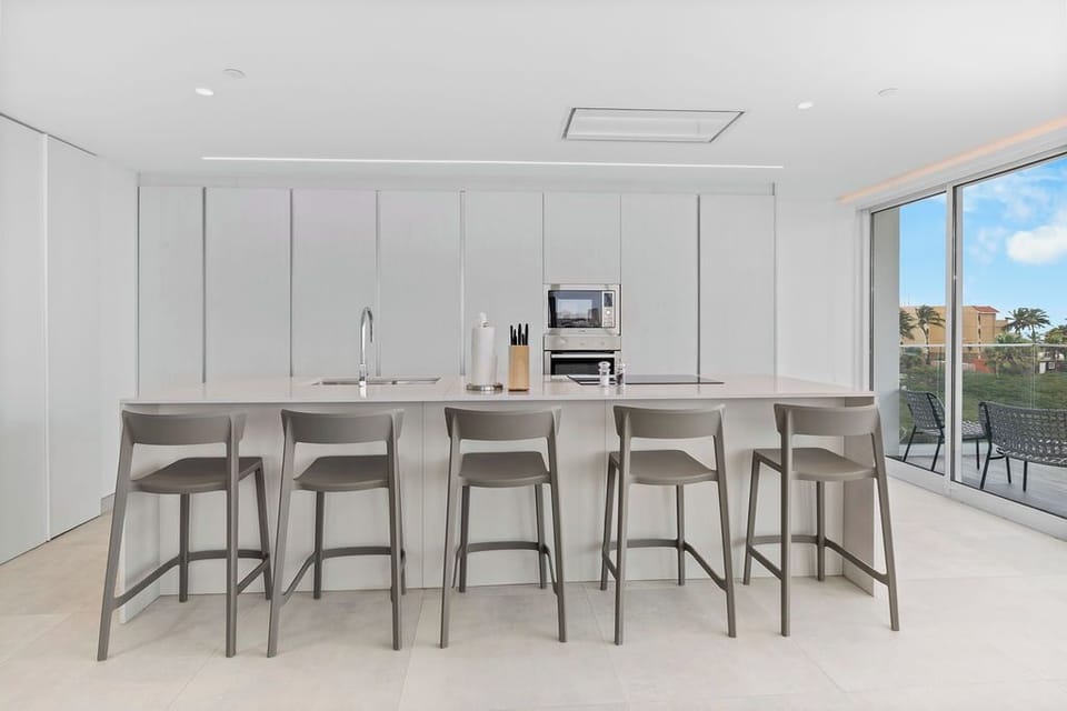 Gather at this sleek kitchen island with five bar stools, a perfect spot for morning coffee or casual meals. Bright and modern, with everything you need to feel at home.