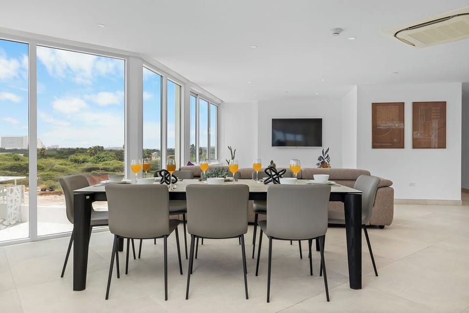 Gather around the spacious dining table for meals, with natural light streaming through floor-to-ceiling windows and a sleek, modern living area perfect for unwinding together.