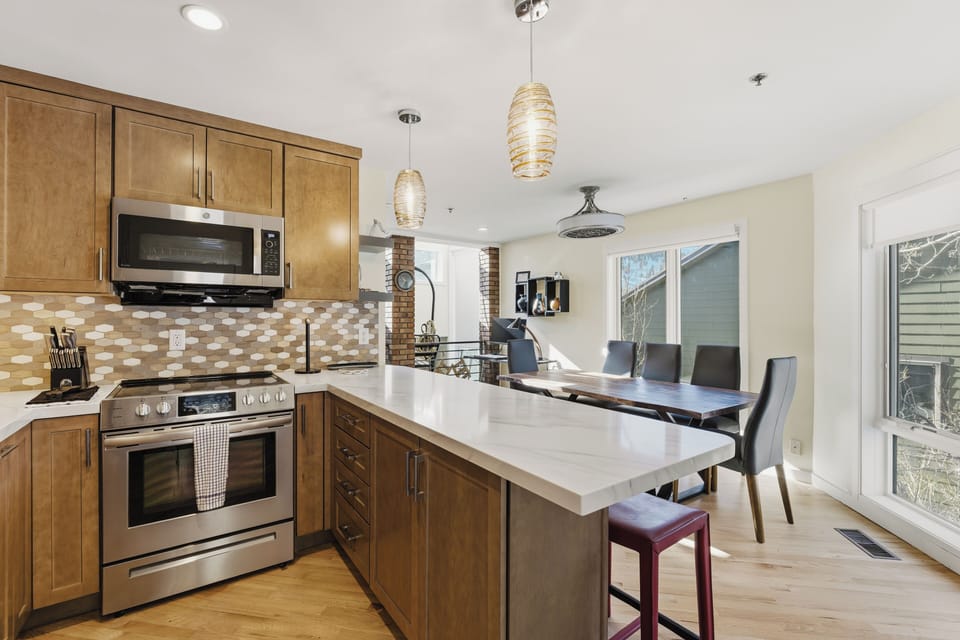 This modern kitchen includes stainless steel appliances, a spacious island with seating, and an adjacent dining area perfect for cooking and entertaining.