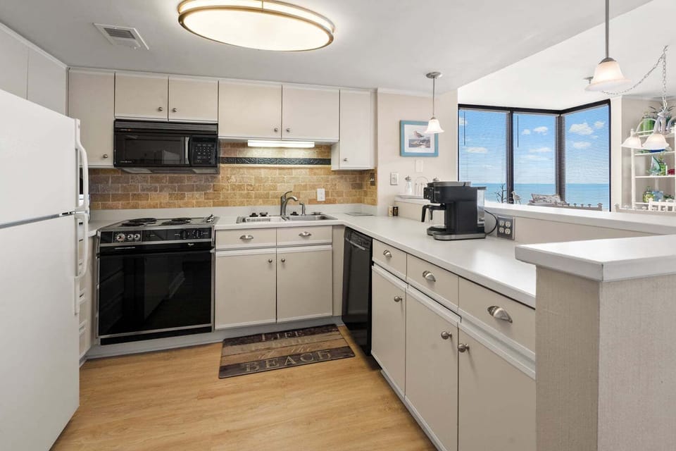 Kitchen with white cabinetry, a coffee maker and an ocean view from the window at Sea Pointe 702, Cherry Grove