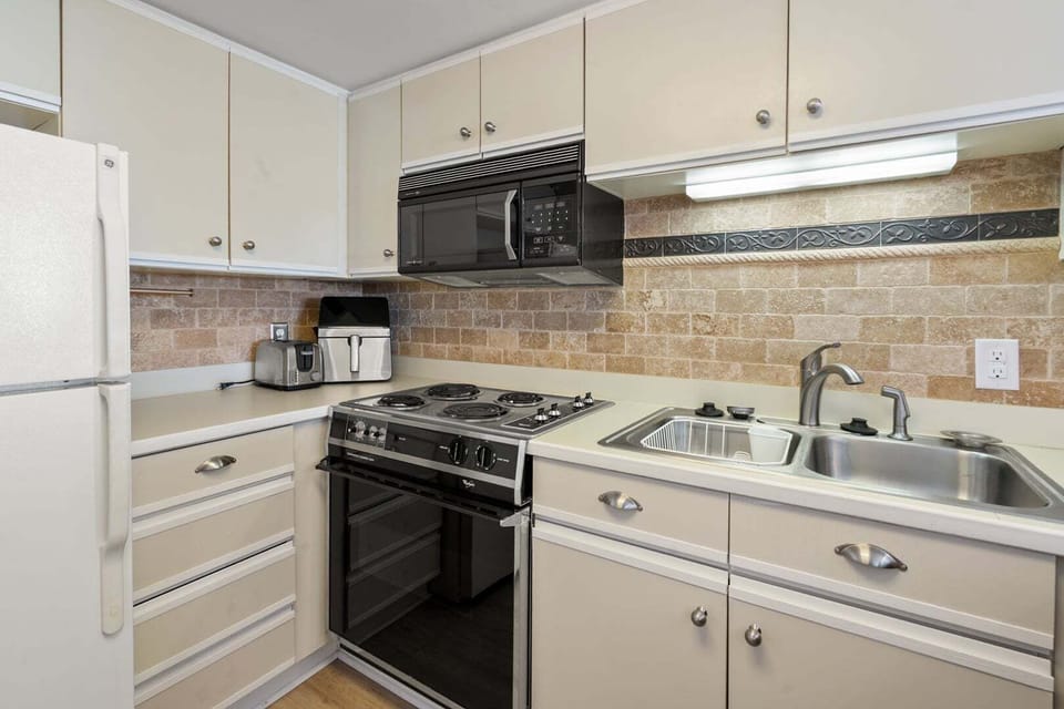 Cooktop, microwave and a deep sink in the fully equipped kitchen at Sea Pointe 702, a 3-bedroom Cherry Grove condo