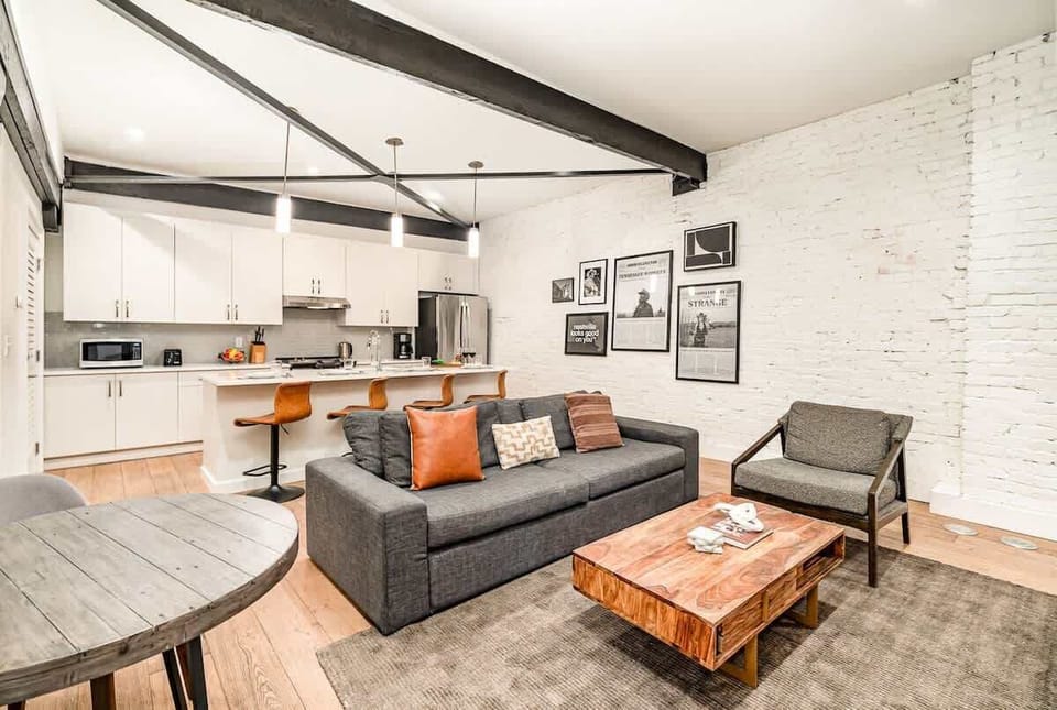 Living room with open-concept design featuring a white brick wall, Smart TV, and comfy sleeper sofa.