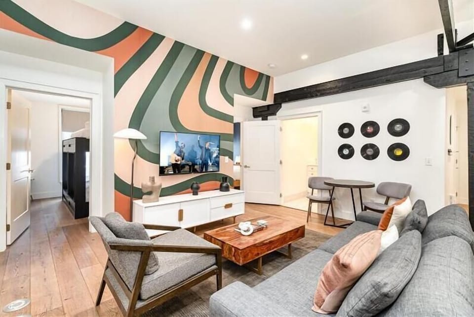 Unit 2: Living room with open-concept design featuring a white brick wall, Smart TV, and comfy sleeper sofa.