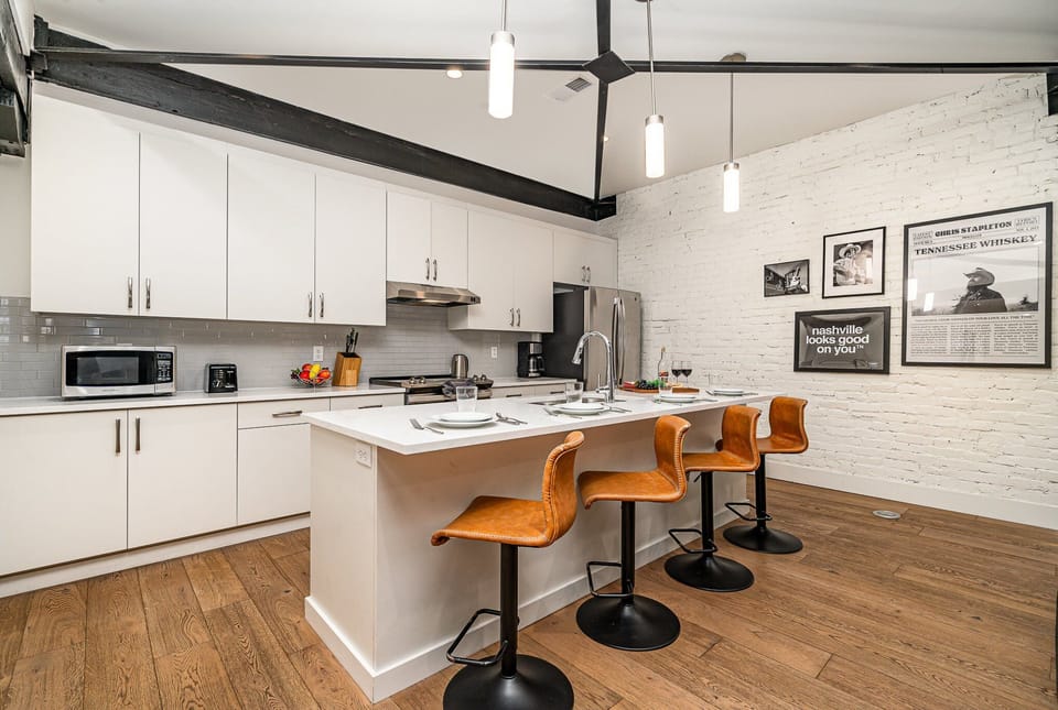 Unit 4: Kitchen with stainless steel appliances, white cabinetry and countertops, and kitchen island with bar seating for 4 guests. (5th Floor)