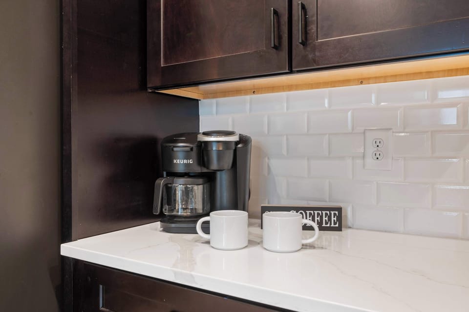 Modern kitchen countertop with a keurig coffee maker and two white mugs for a convenient start to your day.