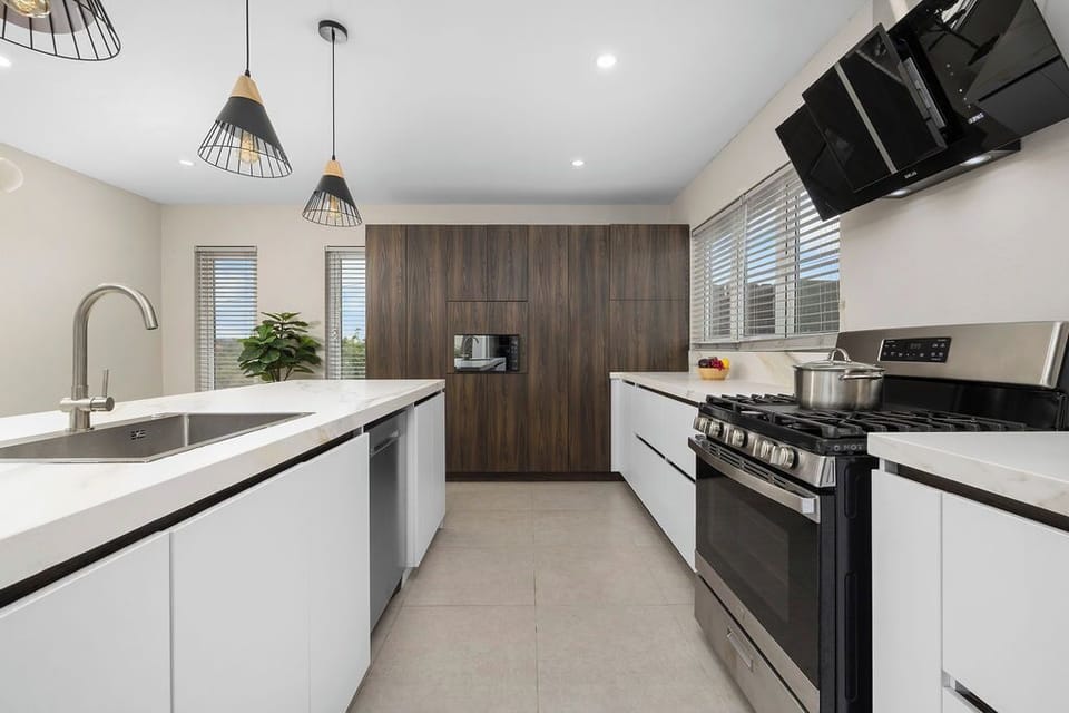 Modern kitchen with sleek cabinets, gas stove, island sink, and lots of light—cook in style!