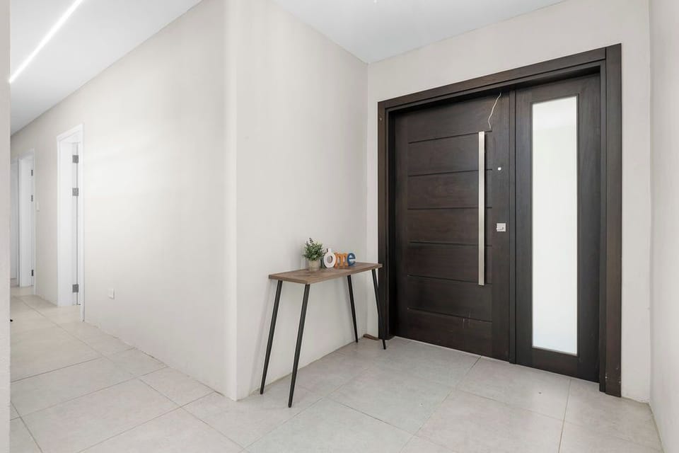 Modern and welcoming entryway with sleek dark wood door and minimal decor, your Aruba getaway starts here!