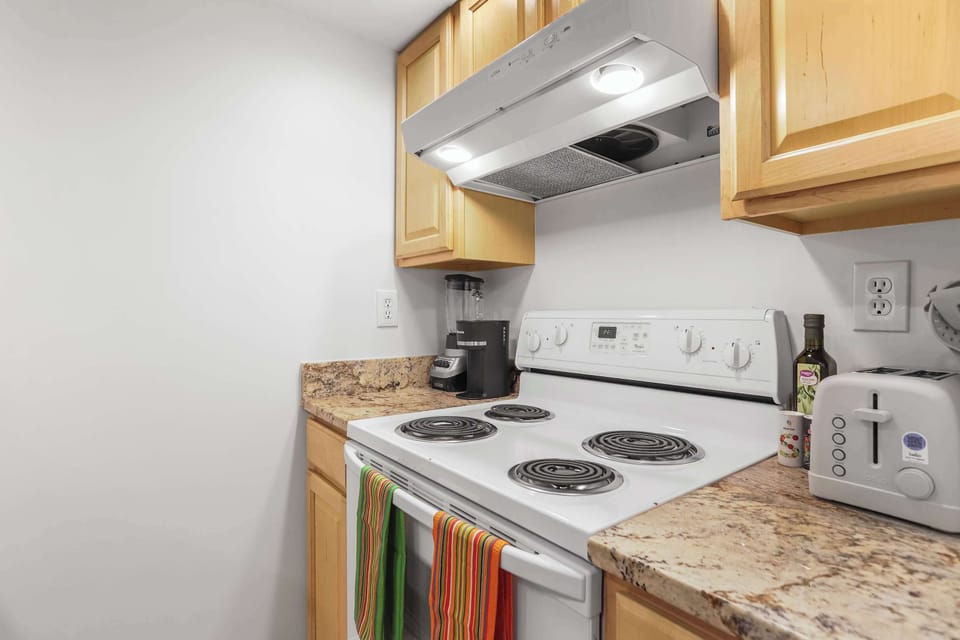 Kitchen with oven and four burner stove and additional storage space. 