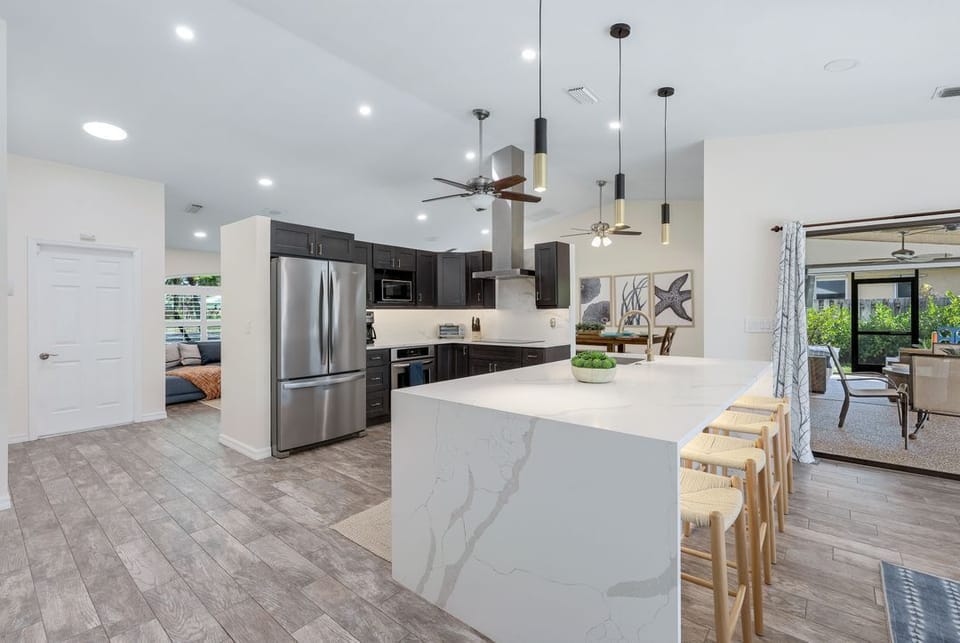 Bright, modern kitchen with a spacious island and stylish seating- perfect for cooking, quick dining, or gathering during your stay.