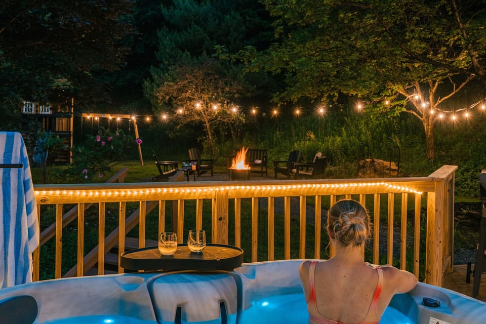 Unwind in the private hot tub overlooking the softly lit backyard — string lights glowing, fire pit crackling, and forest all around. Evenings at Cosmic Ridge Retreat are pure mountain magic.