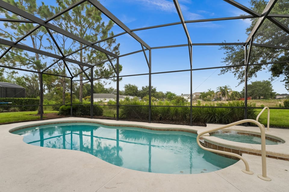 Serene pool view showing screened in pool and spa with partial privacy