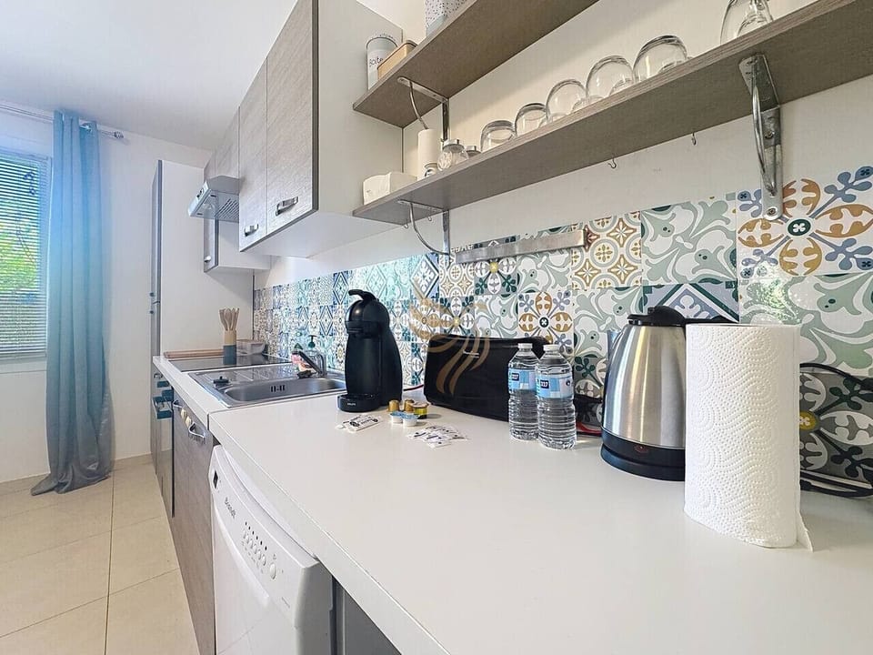 Cuisine moderne, cafetière, plaques de cuisson et lave-vaisselle.