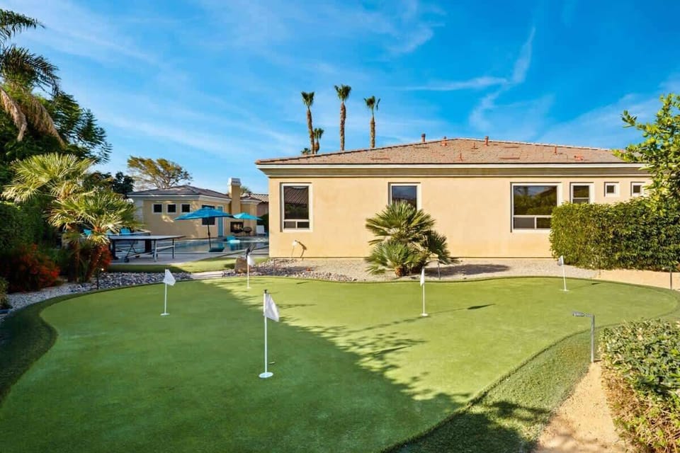 A sunny backyard putting green surrounded by palms — great for a laid-back round anytime.