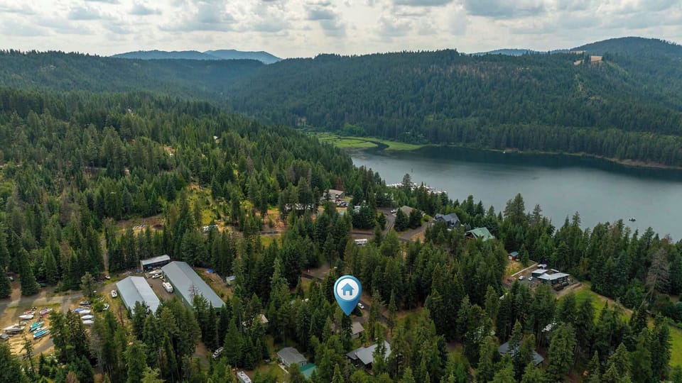 Aerial view of a forested lakeside community nestled among rolling mountains and evergreen trees.