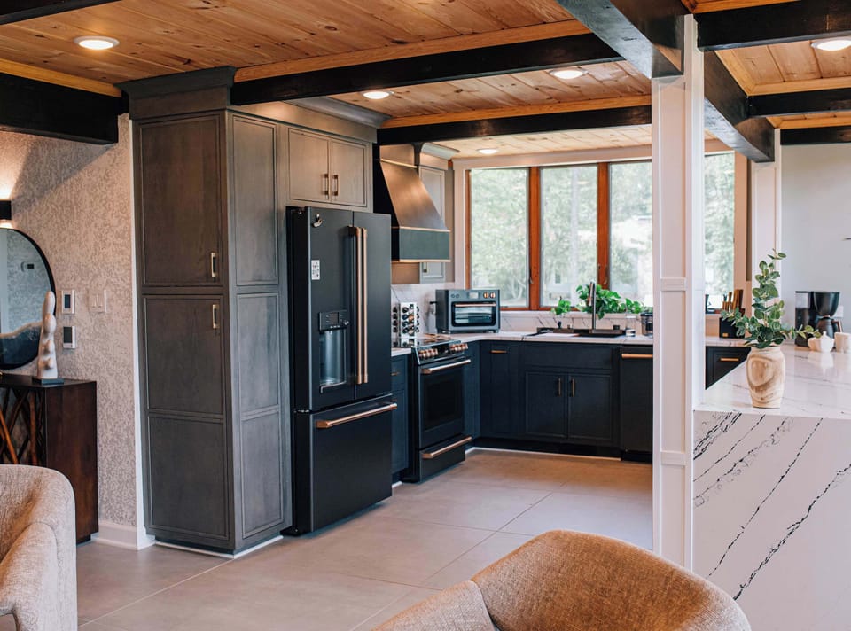 This chef’s kitchen is as refined as it is functional, with matte black cabinetry, pro-grade appliances, and natural wood accents. A beautifully appointed space designed for connection.