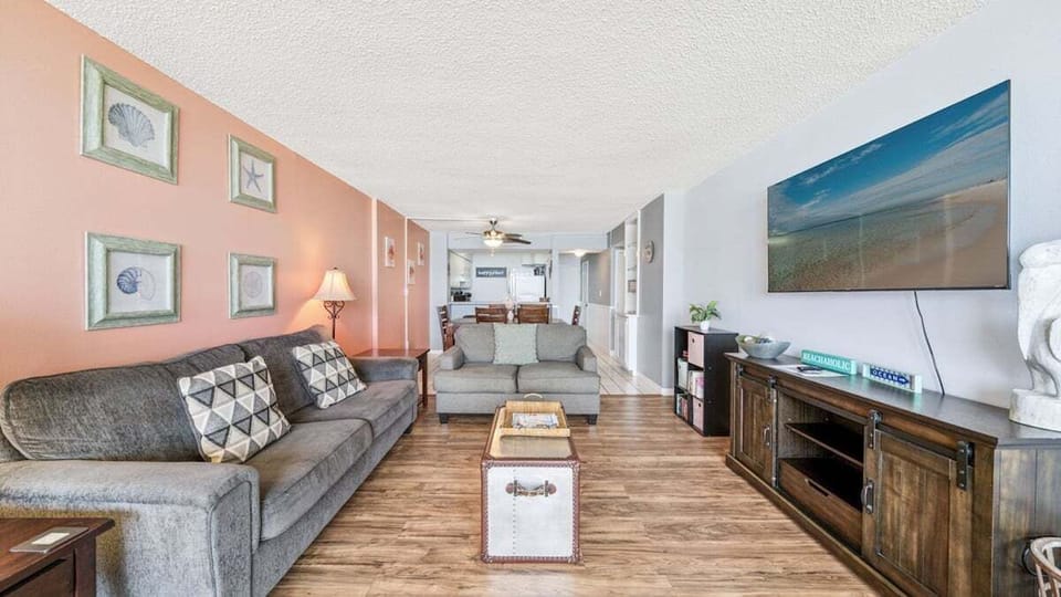 Cozy open-concept living and dining area with beachy decor, smart TV, and comfy seating—ideal for relaxing after beach days.