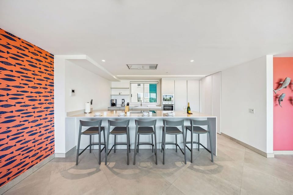 Gather around this stylish kitchen island where vibrant coastal décor meets modern convenience—your perfect spot for morning coffee or evening cocktails with views of the sea.