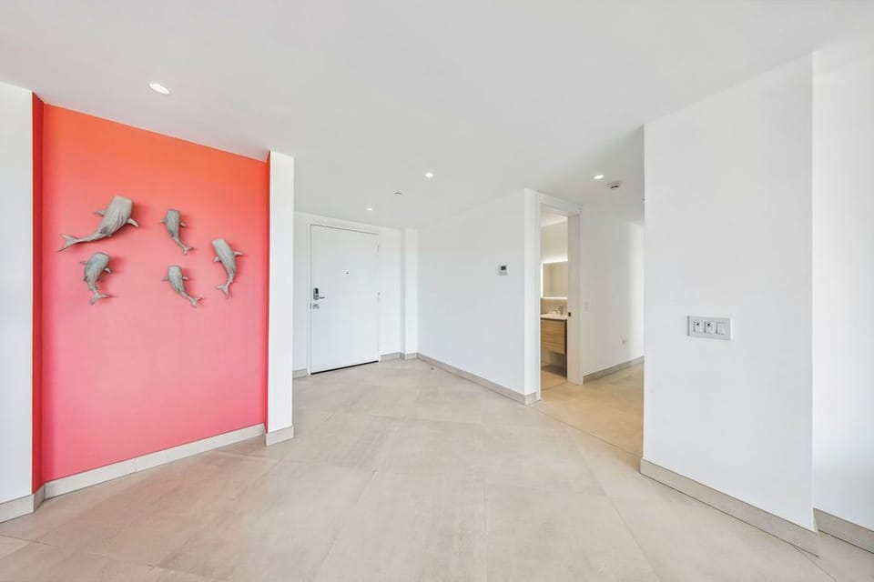 The welcoming entryway features playful dolphin art on a vibrant coral wall, setting a cheerful coastal tone as you arrive at your beachside retreat.