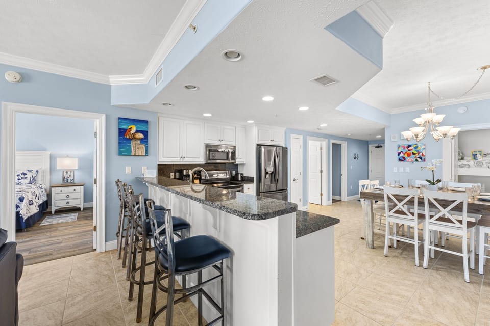 Open kitchen with granite countertops and seating for four in a modern coastal-style home