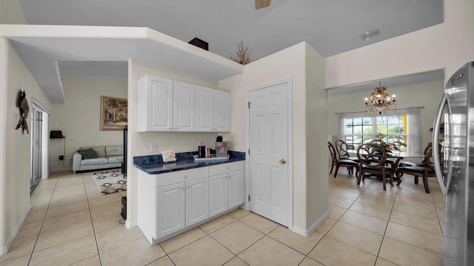 Open floor plan with convenient coffee station, view of the bright dining area with chandelier, and connection to the living room.
