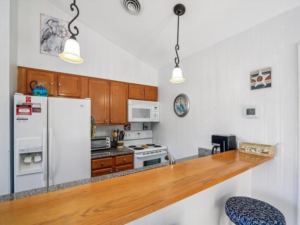 Open-concept kitchen with wood cabinetry and breakfast bar for casual dining.