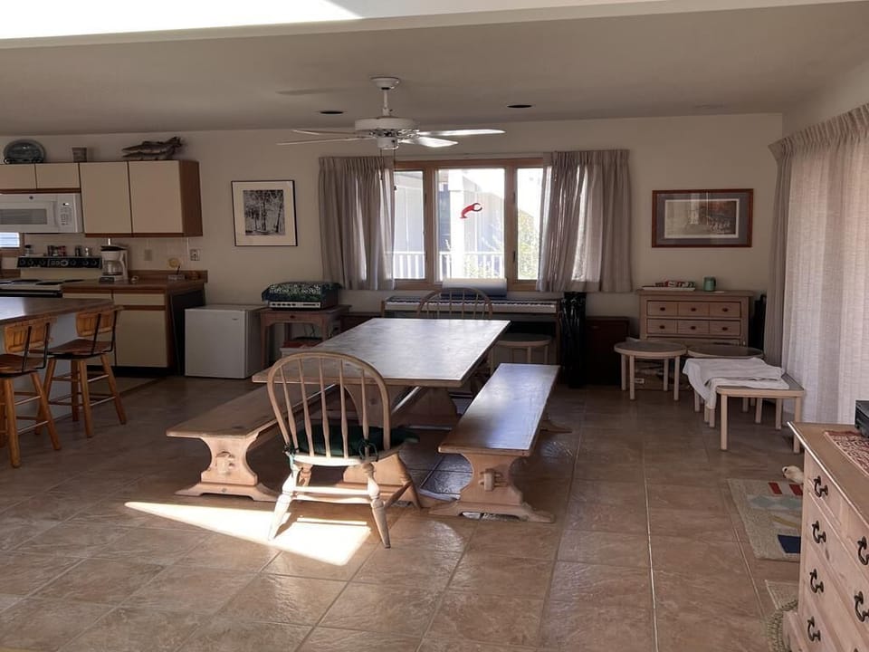 The dining area features a large table and views from wide windows, perfect for family gatherings after beach days.