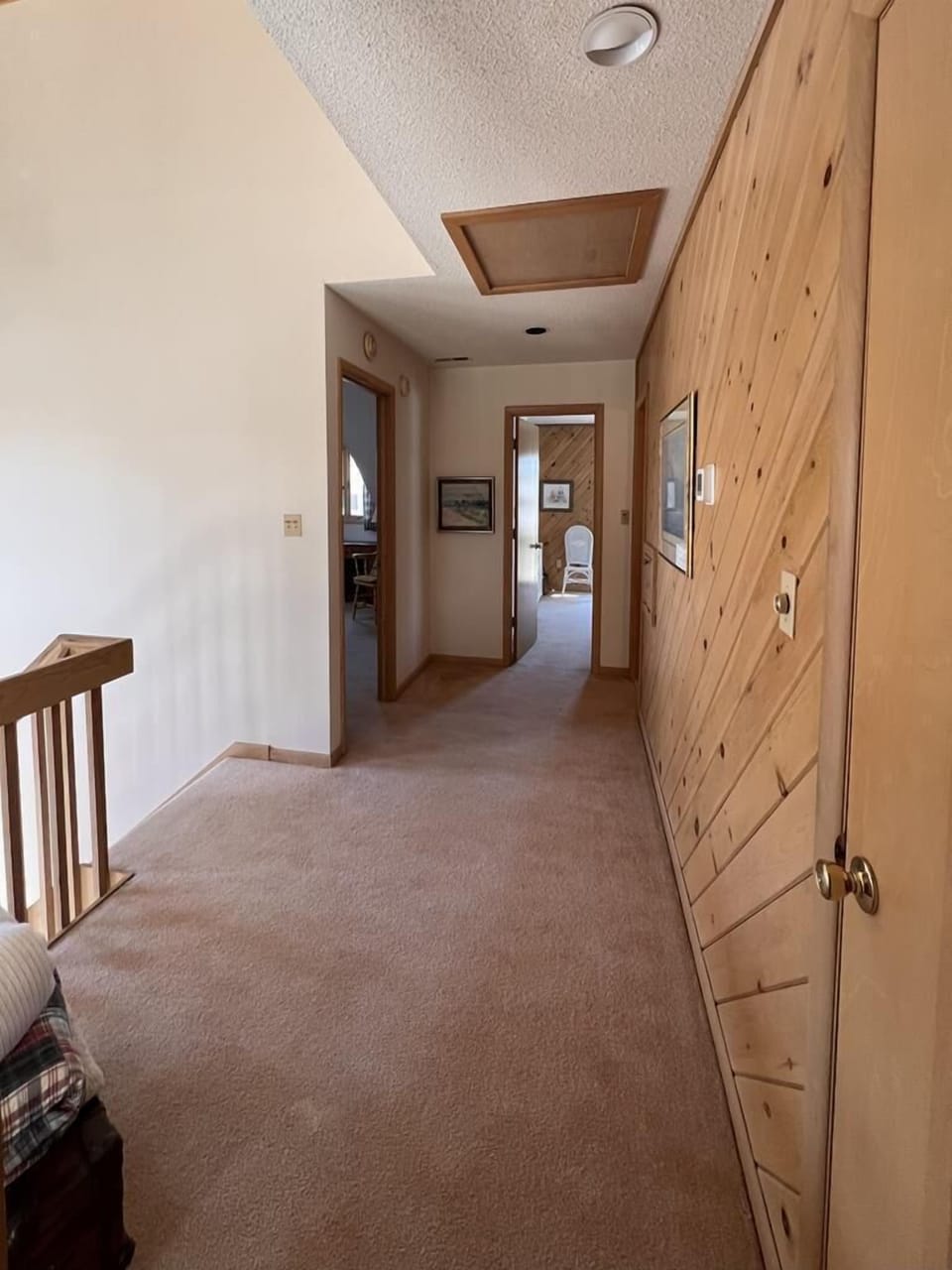 A cozy hallway adorned with natural wood accents, leading to inviting bedrooms and shared spaces of the beach house.
