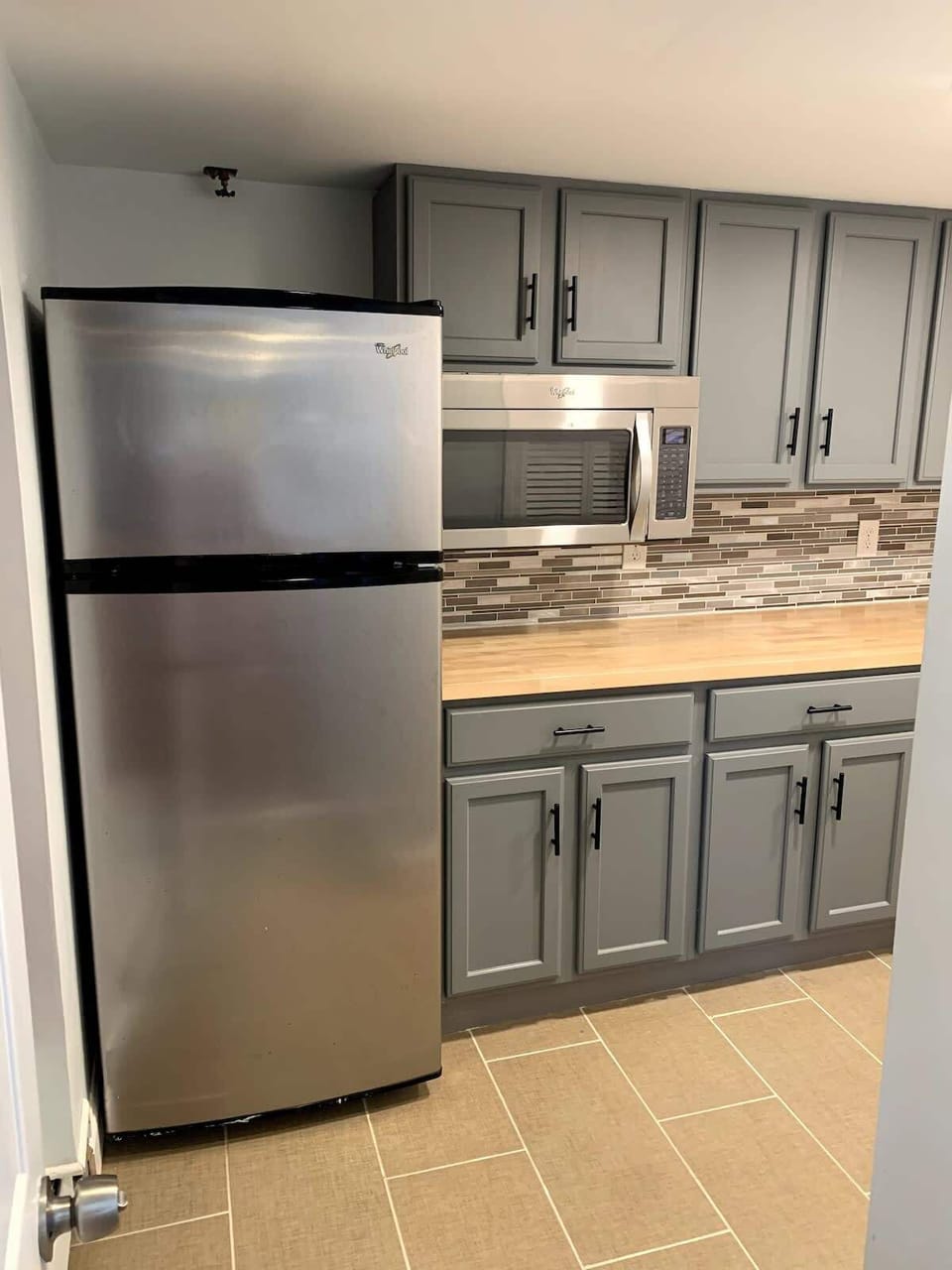 Half-kitchen with a microwave,  a large fridge, an air fryer/mini-oven, and a coffee maker. No conventional stove, kitchen sink or dishwasher.  